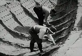 Black and white photograph showing two excavators working in the ship impression at Sutton Hoo